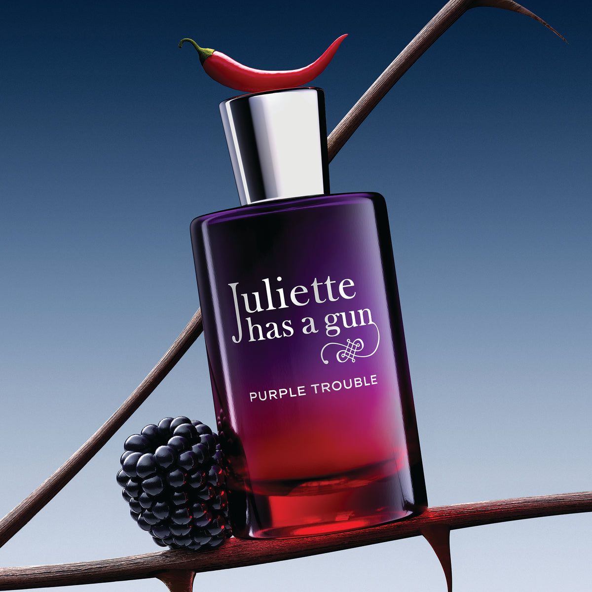 Juliette has a gun Purple Trouble perfume bottle with a red chili pepper on top and a blackberry next to it, set against a blue gradient background with thorny branches.