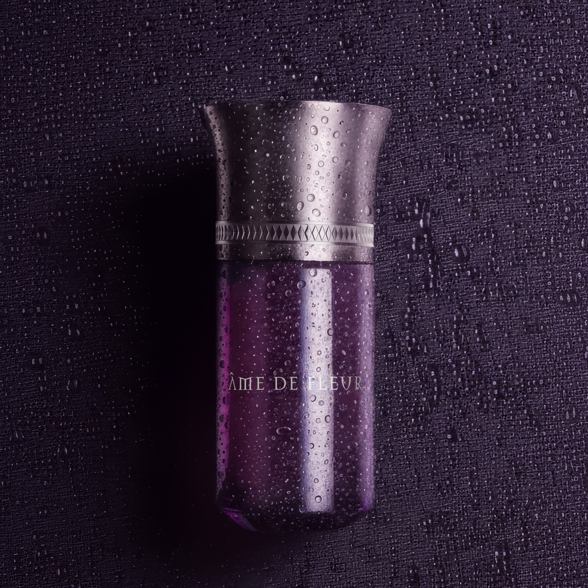 Purple perfume bottle with decorative cap on a textured black background