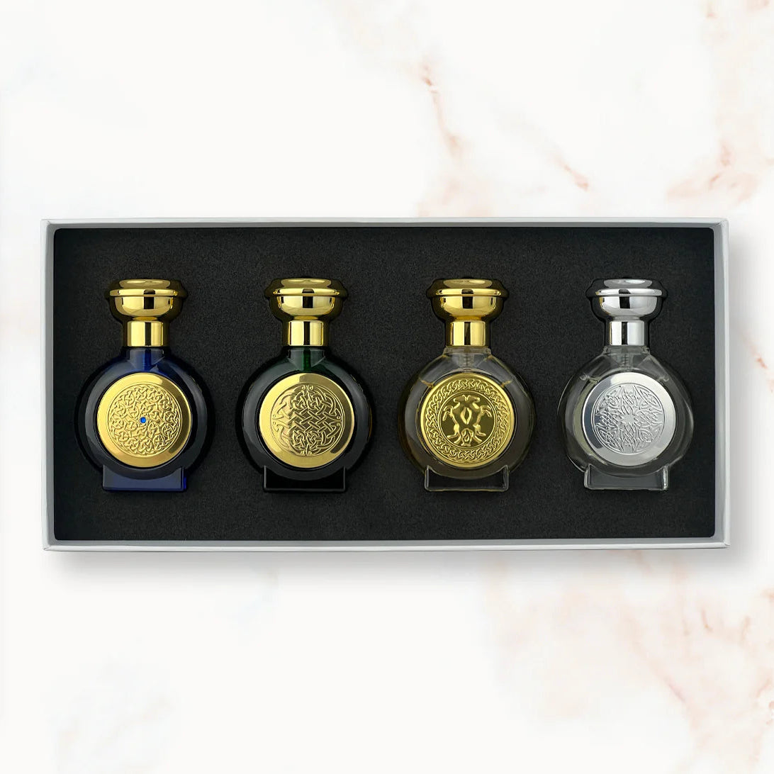 Set of four perfume bottles with gold and silver caps in a box on a marble surface